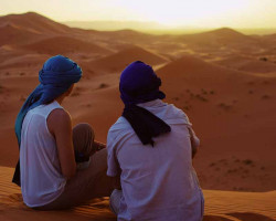 Christian couple gazing at sunset lit sand dunes saudi arabia
