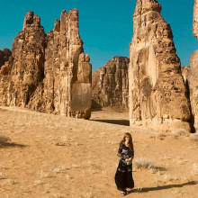Woman with black skirt walking back from exploring Saudi Arabia Rock formations thumbnail