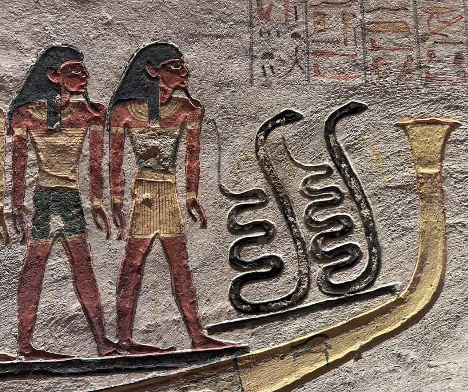 Painted tomb relief from the Valley of the Kings showing two figures towing the solar barque beside large coiled serpents from the Book of Gates