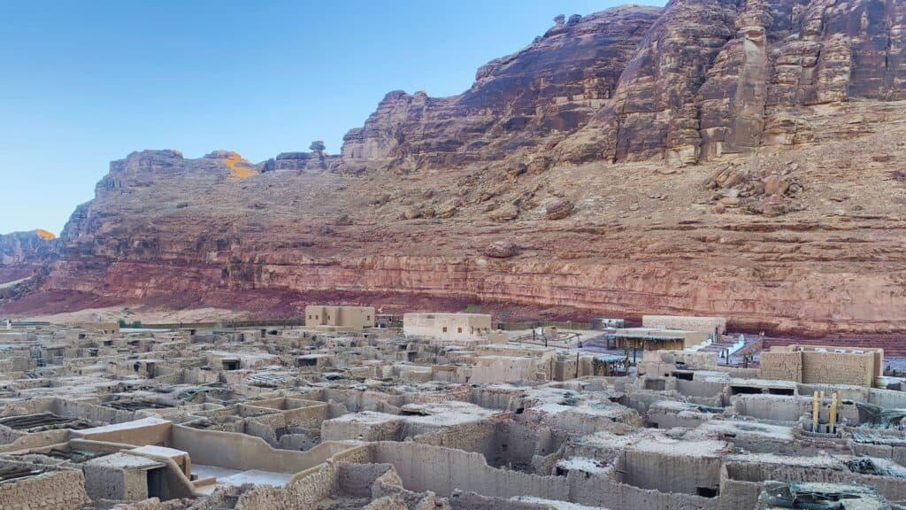 Roofless mud-brick houses of AlUla Old Town packed below a red sandstone escarpment, northwest Saudi Arabia.