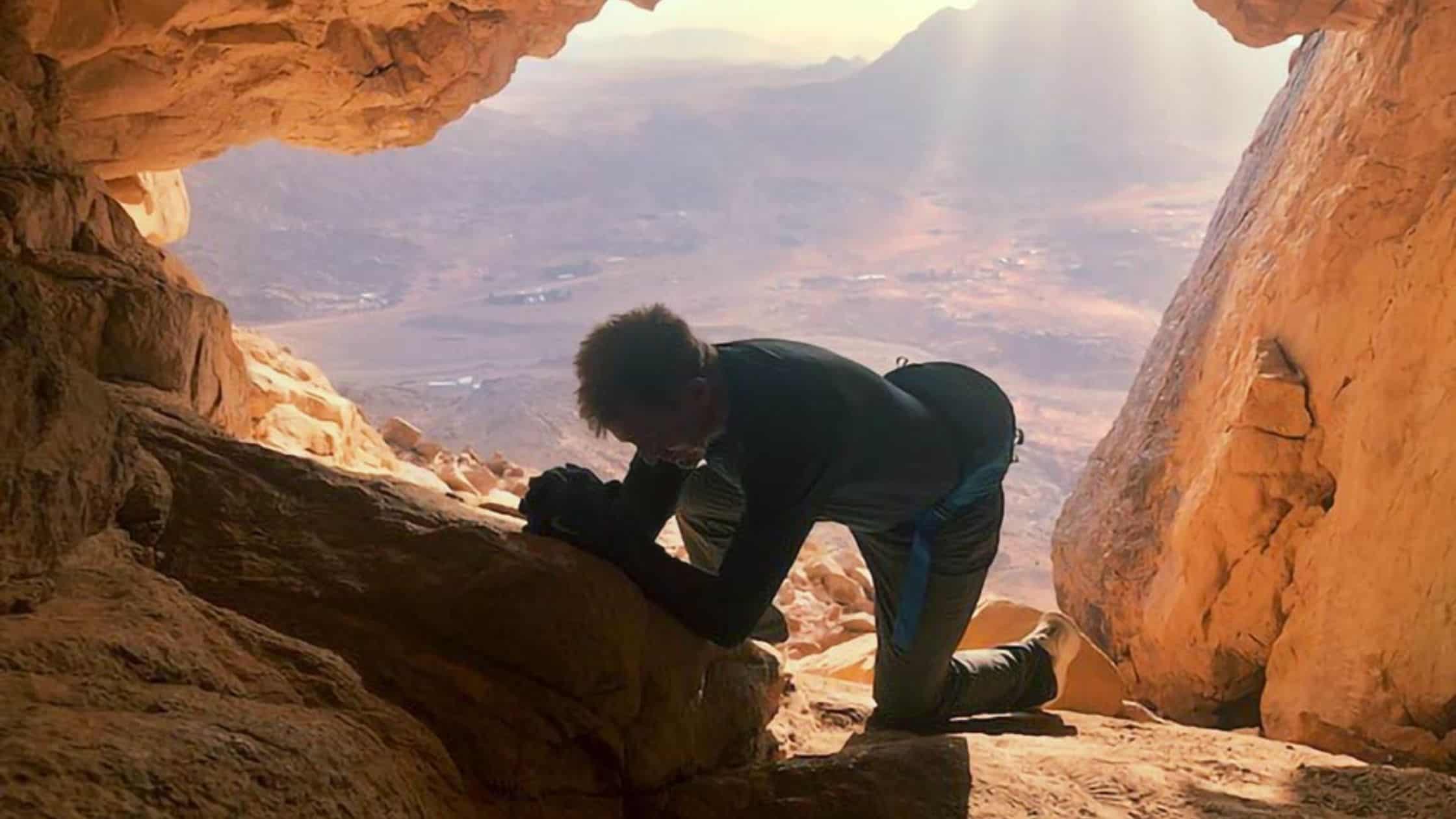 A man kneels in prayer inside Elijah's cave.