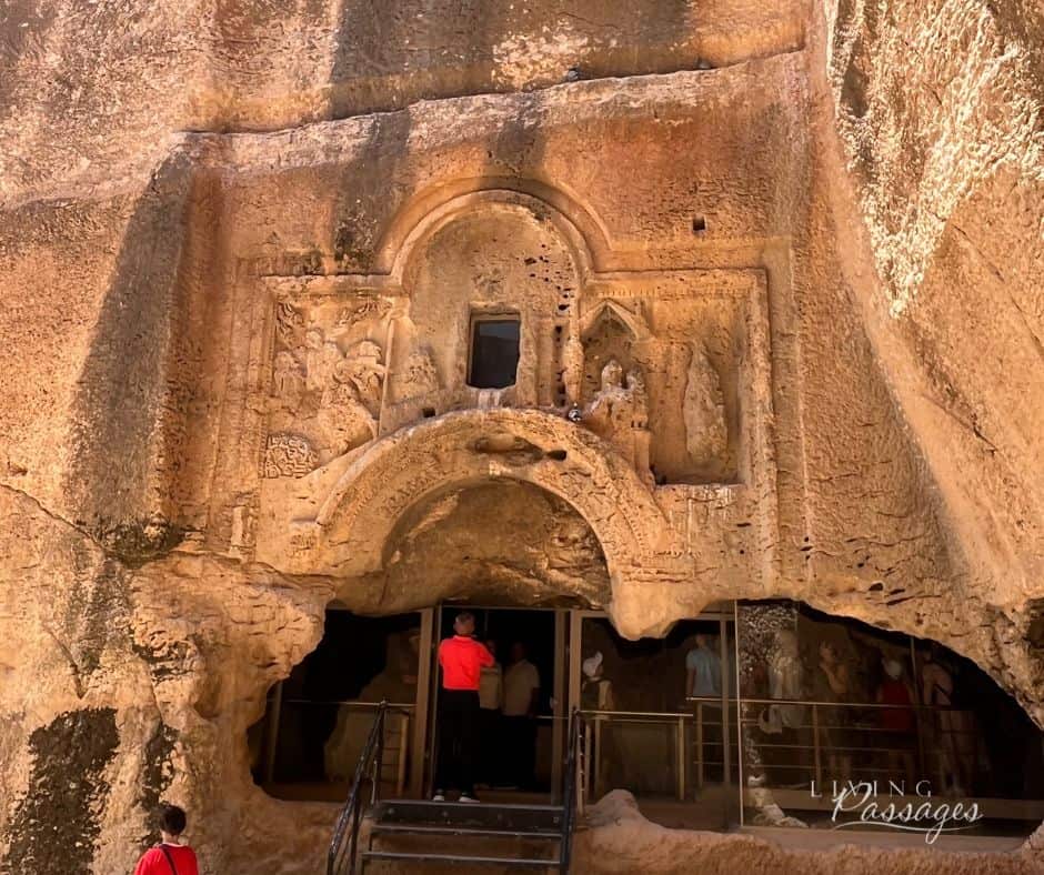 The rock-cut entrance to the gallery grave at Dara, southeastern Turkey, with the sixth-century Ezekiel relief carved into the cliff face above the doorway and visitors entering below.
