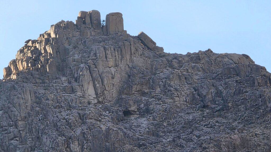 The peak of Jabal Maqla (Lesser), the Cave of Elijah visible on the rock face and an almond tree on the crest above.
