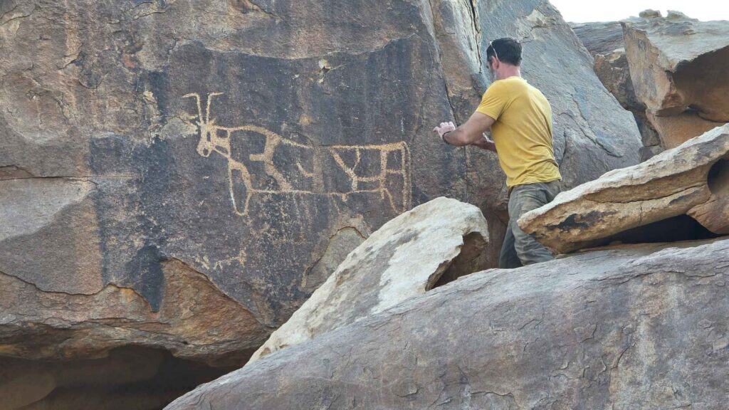 Joel Richardson photographing a large carved bovine on a dark rock face at the golden calf altar Jabal al-Lawz
