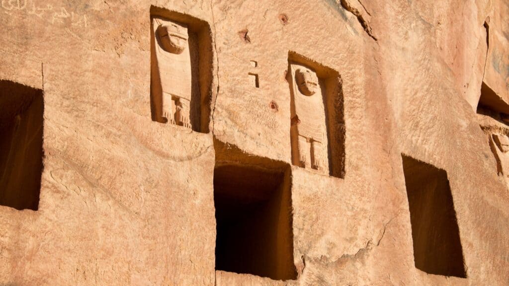 Rock-cut tombs at Dedan with lion sculptures carved in relief above them, in the cliff face at AlUla, Saudi Arabia.