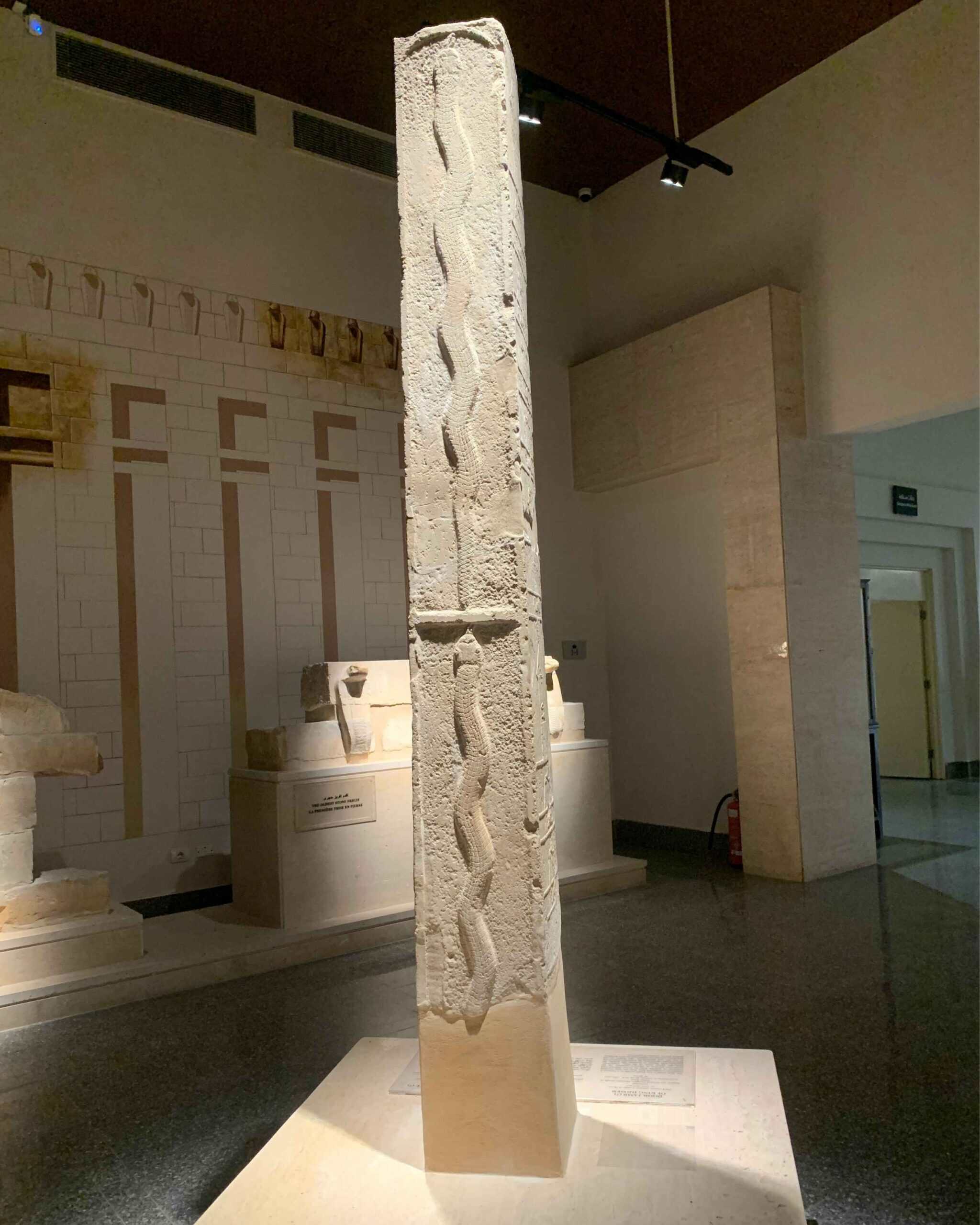 Tall limestone pillar carved with entwined serpents from King Djoser's funerary complex, displayed at the Imhotep Museum, Saqqara