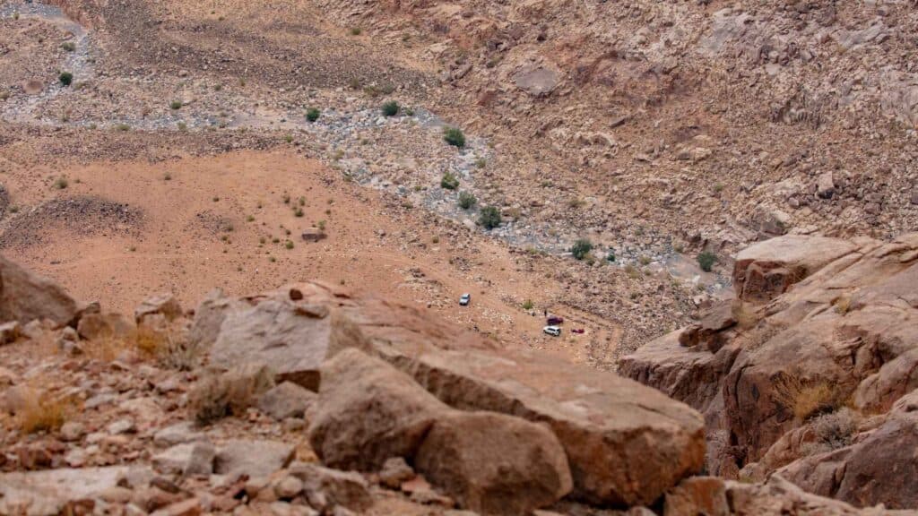 The view down from the Cave of Elijah to the valley floor, with vehicles parked near the Moses altar site far below.