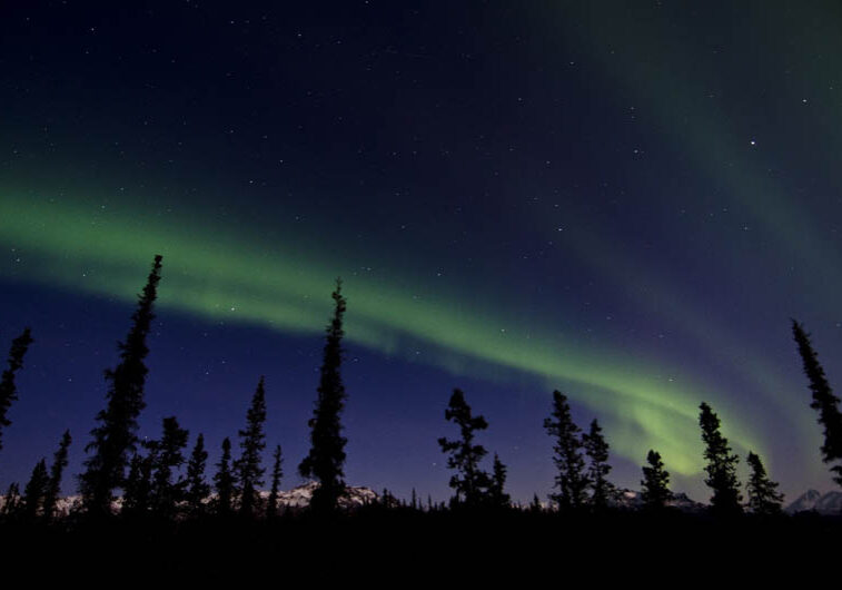 A green streak from the Aurora Borealis across the Alaskan night sky